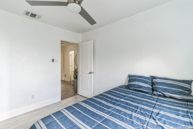 bedroom featuring wood finished floors, baseboards, a ceiling fan, and visible vents