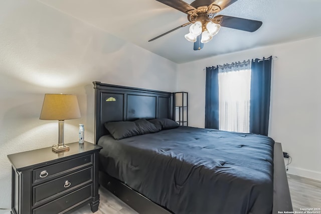 bedroom featuring light wood-type flooring, baseboards, and a ceiling fan