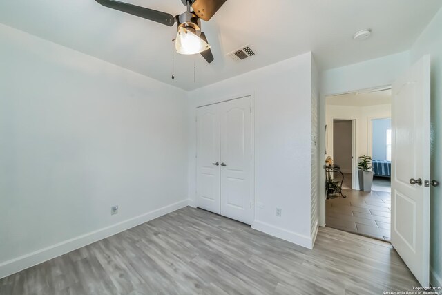 unfurnished bedroom with light wood-style flooring, a closet, baseboards, and visible vents