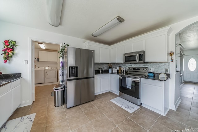 kitchen featuring stainless steel appliances, white cabinets, independent washer and dryer, and dark countertops