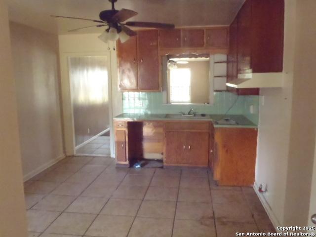 335 Hot Wls, San Antonio, TX 78223 - kitchen featuring light tile patterned floors, ceiling fan, brown cabinetry, and light countertops