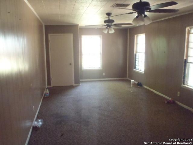 335 Hot Wls, San Antonio, TX 78223 - unfurnished room featuring baseboards, visible vents, ceiling fan, and wooden walls