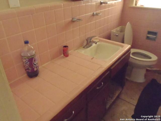 335 Hot Wls, San Antonio, TX 78223 - half bath with tile walls, toilet, tile patterned flooring, and vanity