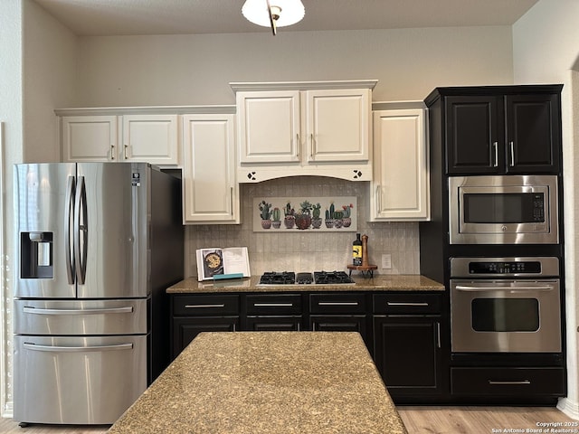 23407 Treemont Park, San Antonio, TX 78261 - kitchen with stainless steel appliances, dark cabinets, white cabinetry, decorative backsplash, and light wood-type flooring