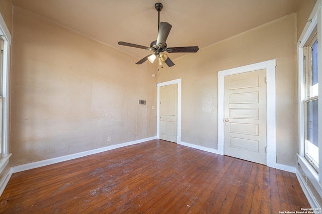 spare room with wood-type flooring, visible vents, baseboards, and ceiling fan