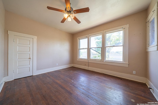 spare room with dark wood-type flooring, ceiling fan, and baseboards