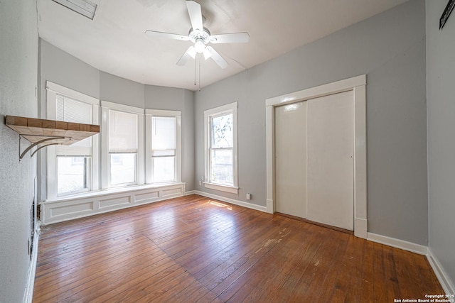 interior space featuring a closet, wood-type flooring, a ceiling fan, and baseboards