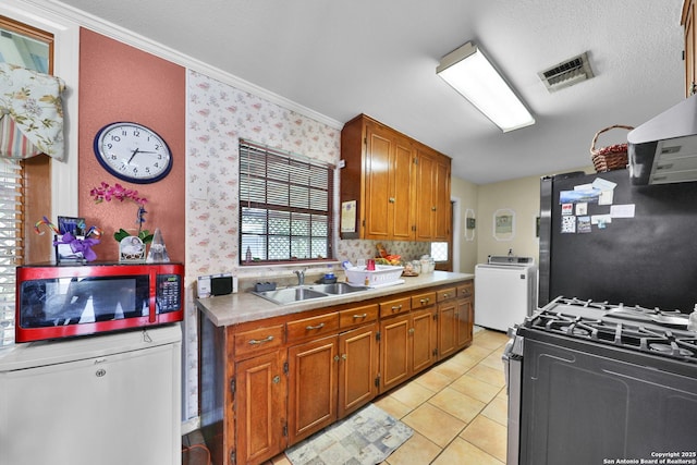 307 Trudell, San Antonio, TX 78213 - kitchen featuring washer / clothes dryer, a sink, light countertops, appliances with stainless steel finishes, and brown cabinets