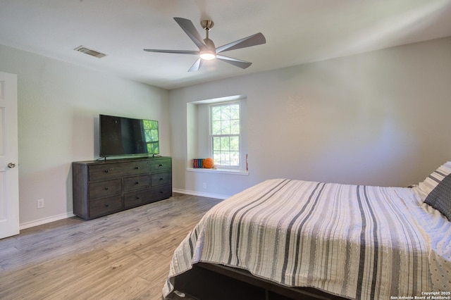 bedroom with wood finished floors, ceiling fan, baseboards, and visible vents
