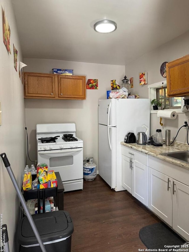 1915 Pasadena St, San Antonio, TX 78201 - kitchen with dark wood-type flooring, white cabinetry, white appliances, and a sink