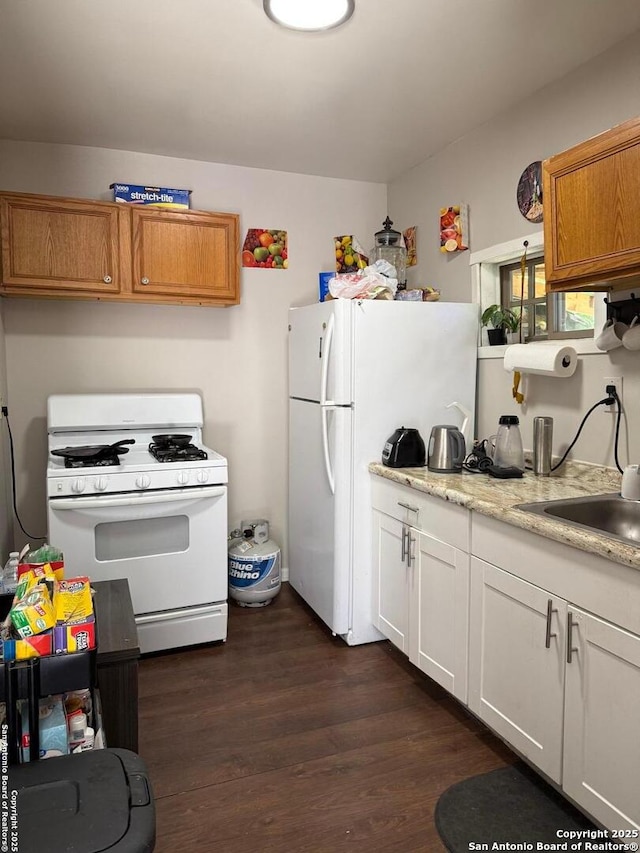 1915 Pasadena St, San Antonio, TX 78201 - kitchen with white appliances, light countertops, white cabinets, dark wood-type flooring, and a sink