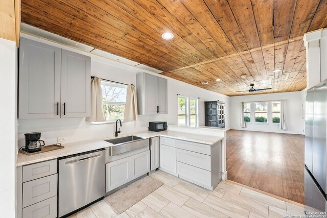 104 Persons St, Stockdale, TX 78160 - kitchen with stainless steel dishwasher, a ceiling fan, gray cabinets, a sink, and open floor plan