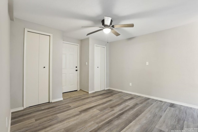1360 Essex, San Antonio, TX 78210 - unfurnished bedroom with wood finished floors, baseboards, a ceiling fan, and multiple closets