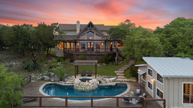 back of property at dusk with a jacuzzi, stairs, an outdoor pool, board and batten siding, and a wooden deck