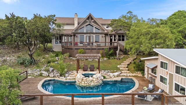 back of property with a pergola, an in ground hot tub, a wooden deck, stairs, and an outdoor pool