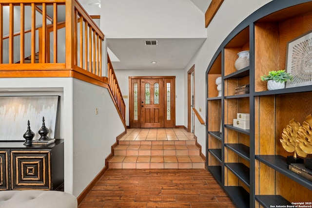tiled foyer with baseboards, stairs, and visible vents