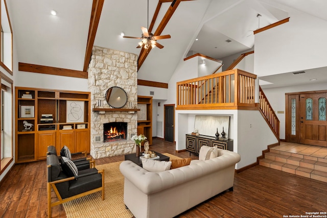 living room with visible vents, ceiling fan, stairway, a stone fireplace, and high vaulted ceiling