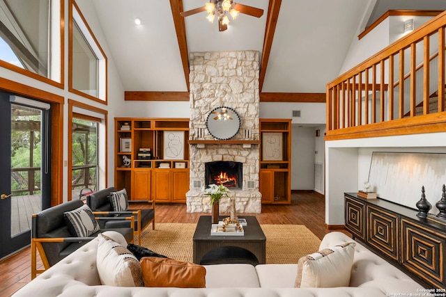 living area with high vaulted ceiling, a ceiling fan, a stone fireplace, beam ceiling, and visible vents