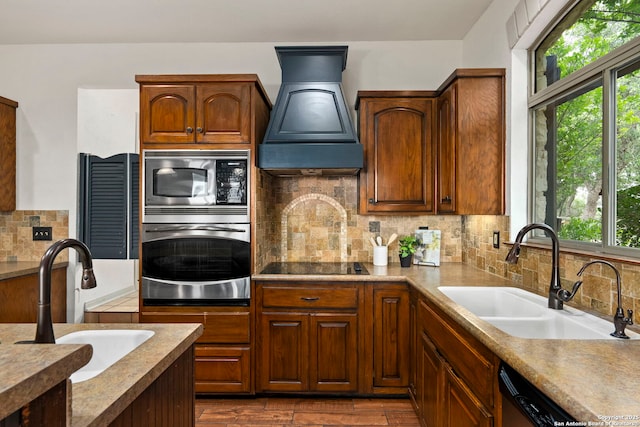 kitchen with premium range hood, backsplash, stainless steel appliances, and a sink