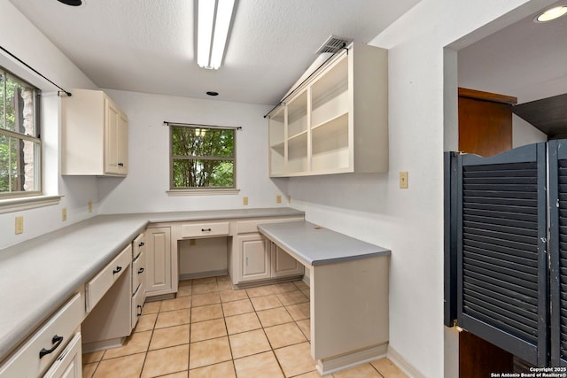 kitchen featuring light tile patterned flooring, light countertops, built in study area, and a healthy amount of sunlight