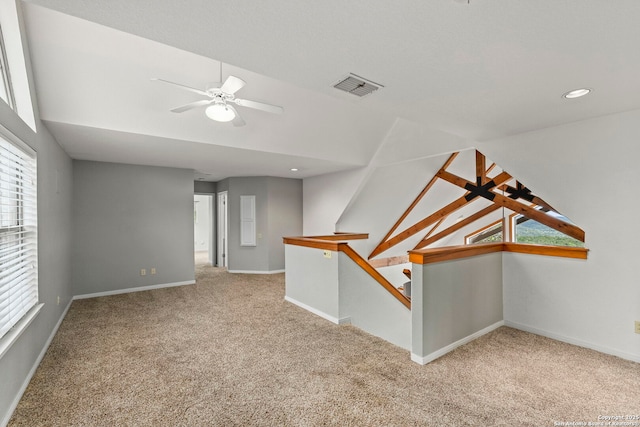 empty room with a ceiling fan, baseboards, lofted ceiling, carpet flooring, and visible vents