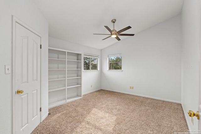 carpeted spare room featuring vaulted ceiling, baseboards, and ceiling fan