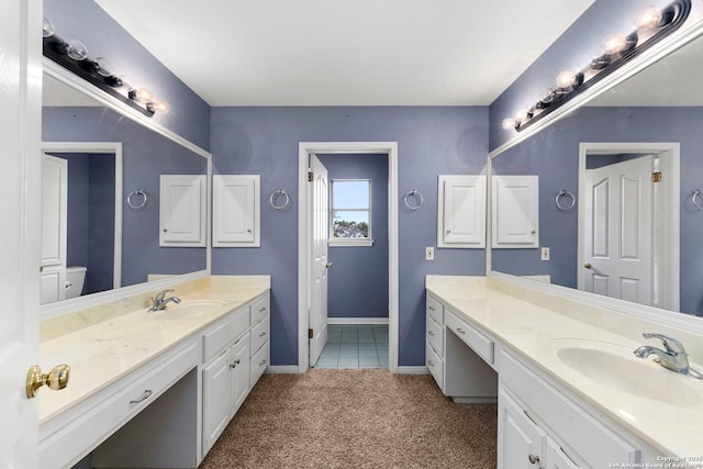 bathroom featuring two vanities, a sink, and baseboards