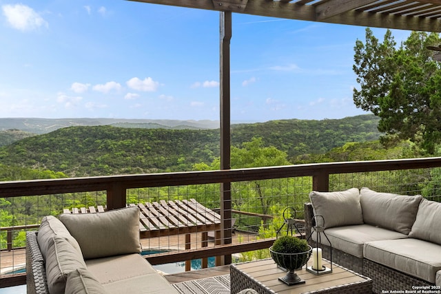 balcony with a mountain view, a view of trees, and an outdoor hangout area