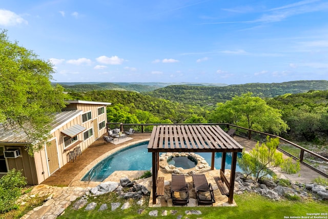 view of swimming pool featuring a view of trees, a pool with connected hot tub, and a wall unit AC