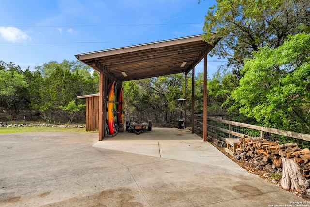exterior space featuring driveway, a carport, and fence