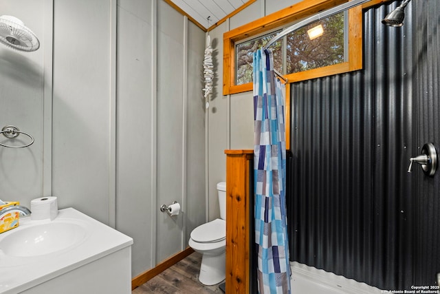 bathroom featuring curtained shower, wood finished floors, toilet, and a sink