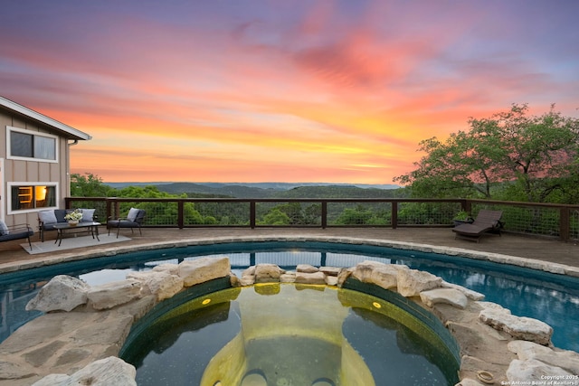 view of pool with a deck with mountain view, a pool with connected hot tub, and an outdoor hangout area