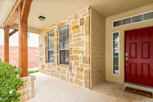 view of exterior entry featuring covered porch and stone siding