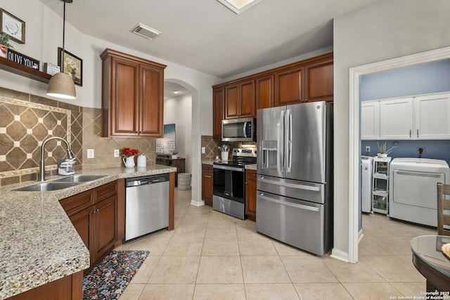 4 Andover Creek Dr, San Antonio, TX 78254 - kitchen with appliances with stainless steel finishes, a sink, arched walkways, washing machine and dryer, and light tile patterned floors