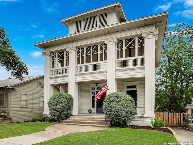 view of front facade featuring a porch, a front lawn, fence, and a balcony