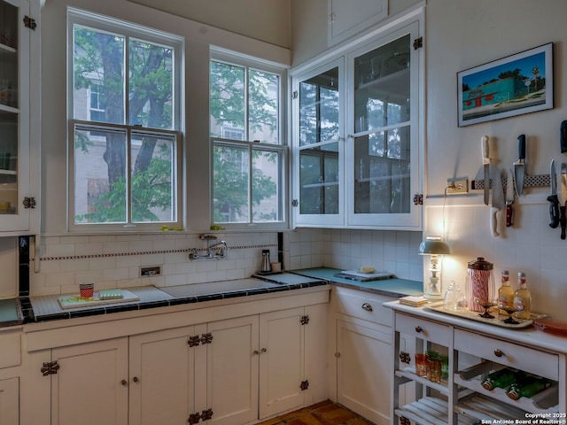 kitchen featuring tile counters, white cabinetry, and backsplash