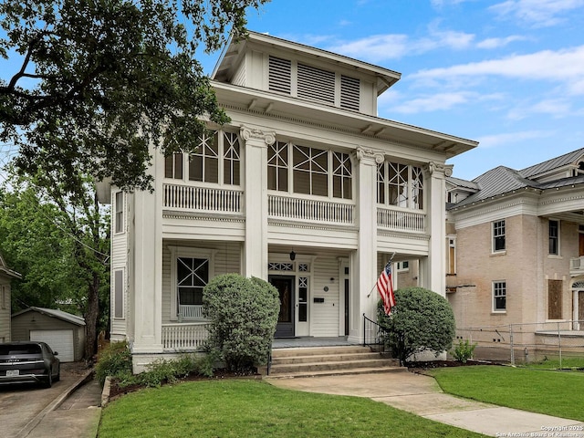 neoclassical / greek revival house with fence, a balcony, a front yard, covered porch, and an outbuilding