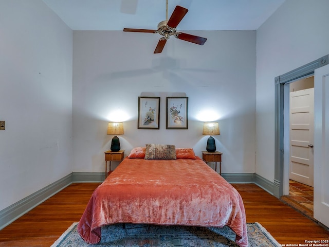 bedroom featuring baseboards, a high ceiling, and wood finished floors