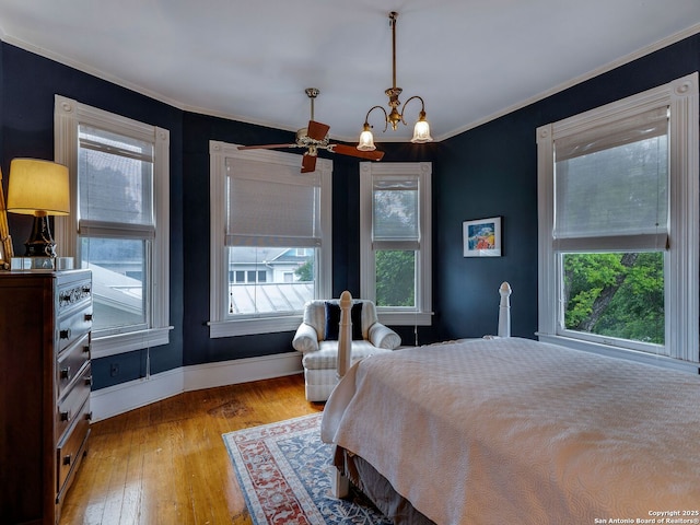 bedroom featuring wood-type flooring, baseboards, an inviting chandelier, and ornamental molding