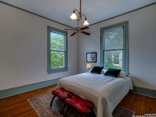 bedroom with crown molding, baseboards, a chandelier, and wood finished floors