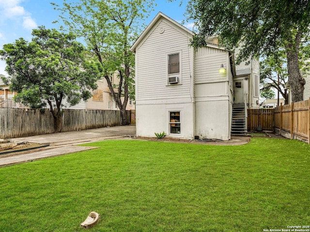 back of property with a fenced backyard, stairs, a lawn, and cooling unit