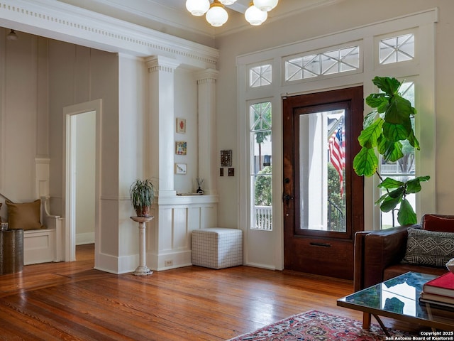 foyer featuring wood-type flooring, a notable chandelier, ornamental molding, and a wealth of natural light