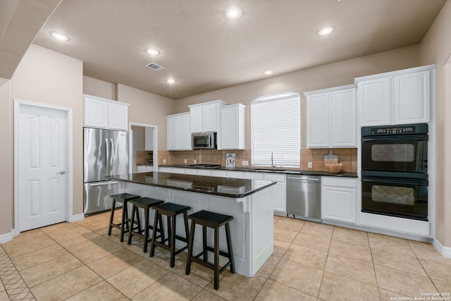 kitchen with visible vents, white cabinets, a kitchen island, appliances with stainless steel finishes, and a sink