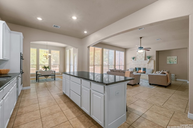 kitchen featuring visible vents, white cabinets, dark countertops, ceiling fan with notable chandelier, and a kitchen island