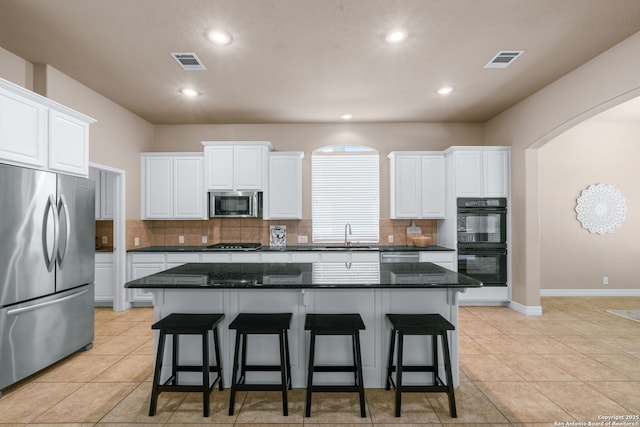 kitchen featuring white cabinets, arched walkways, visible vents, and stainless steel appliances
