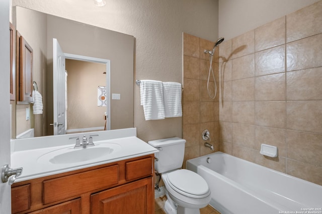 bathroom with toilet, vanity, a textured wall, and washtub / shower combination