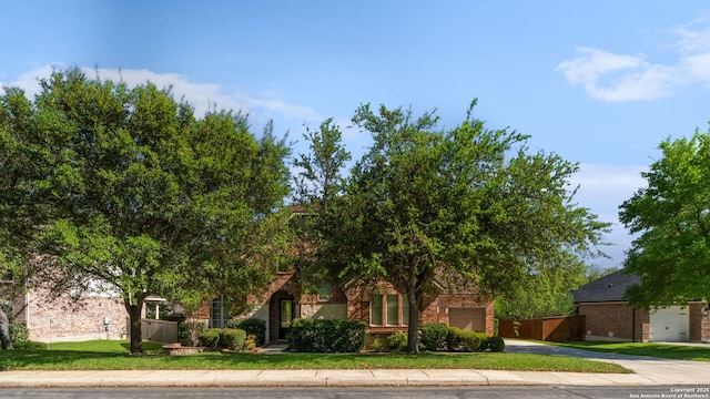 obstructed view of property with an attached garage, driveway, a front lawn, and brick siding