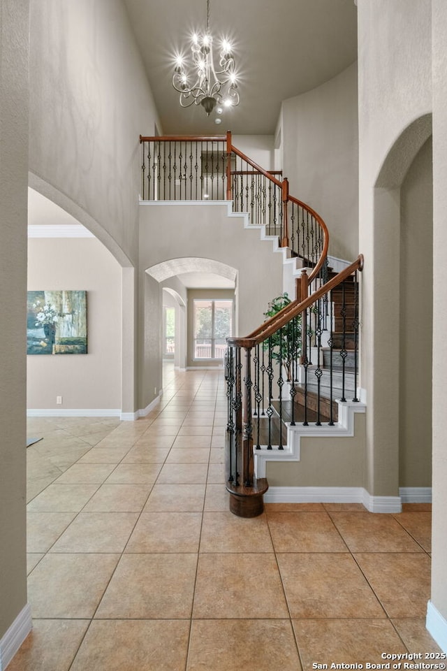 stairs featuring baseboards, arched walkways, and a notable chandelier