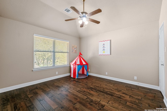 recreation room with dark wood-type flooring, a ceiling fan, vaulted ceiling, visible vents, and baseboards