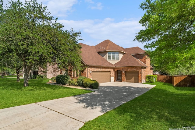 french country inspired facade featuring concrete driveway, a front yard, brick siding, and fence